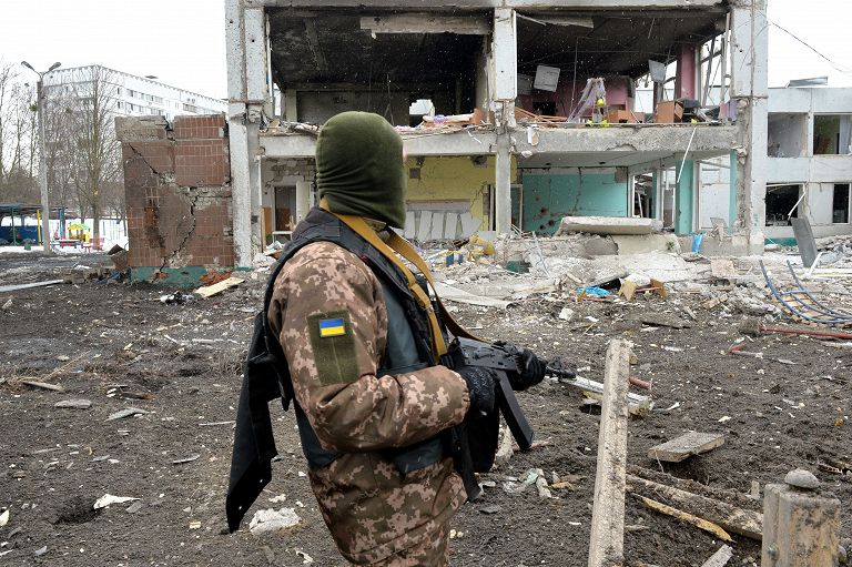 Un membro delle Forze di difesa territoriale ucraine davanti a un edificio colpito da un bombardamento nella seconda città più grande dell'Ucraina, Kharkiv, l'8 marzo 2022