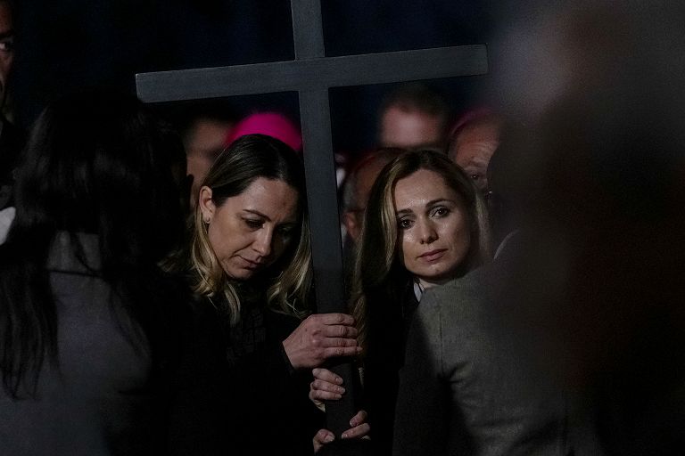 Le due infermiere, Albina dalla Russia, a destra, e Irina, dall'Ucraina, tengono la croce mentre partecipano alla Via Crucis