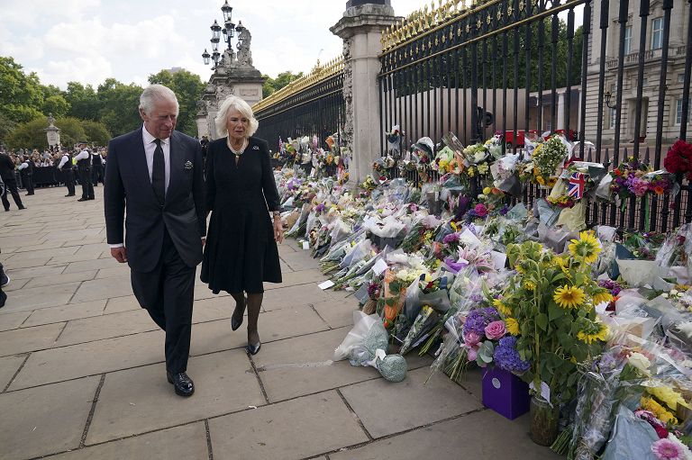 Il re della Gran Bretagna Carlo III, a sinistra, e Camilla, la regina consorte, passano davanti a tributi floreali lasciati fuori Buckingham Palace